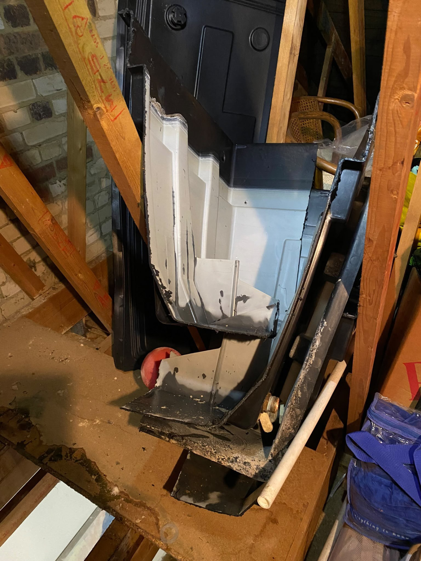 Old plastic cold water tank cut up for removal from a London loft