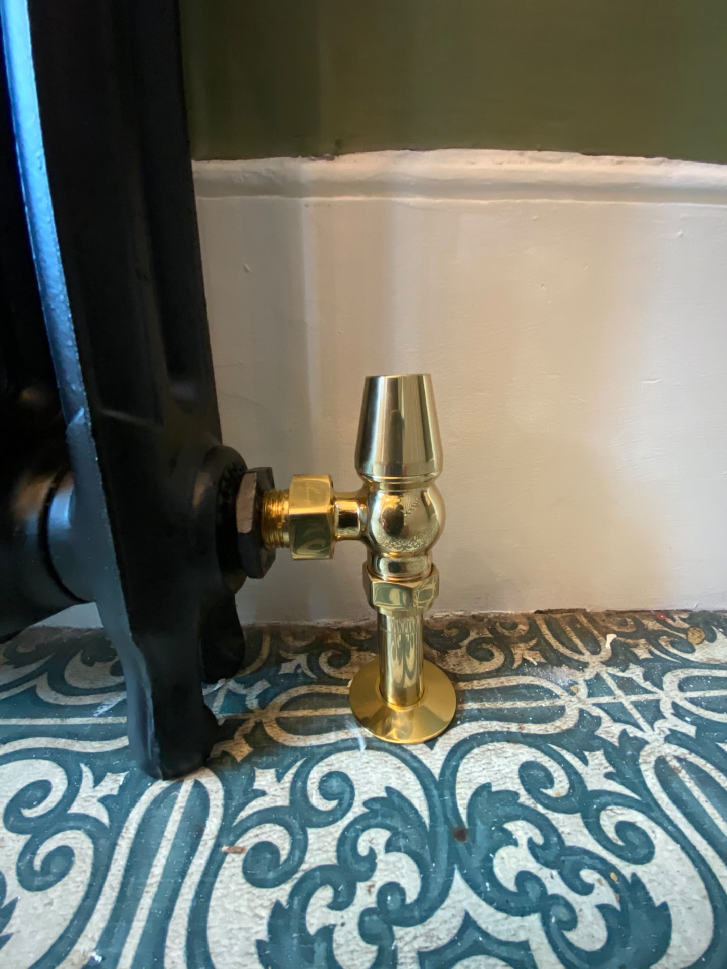Polished brass radiator valve fitted to a cast iron radiator in a London home