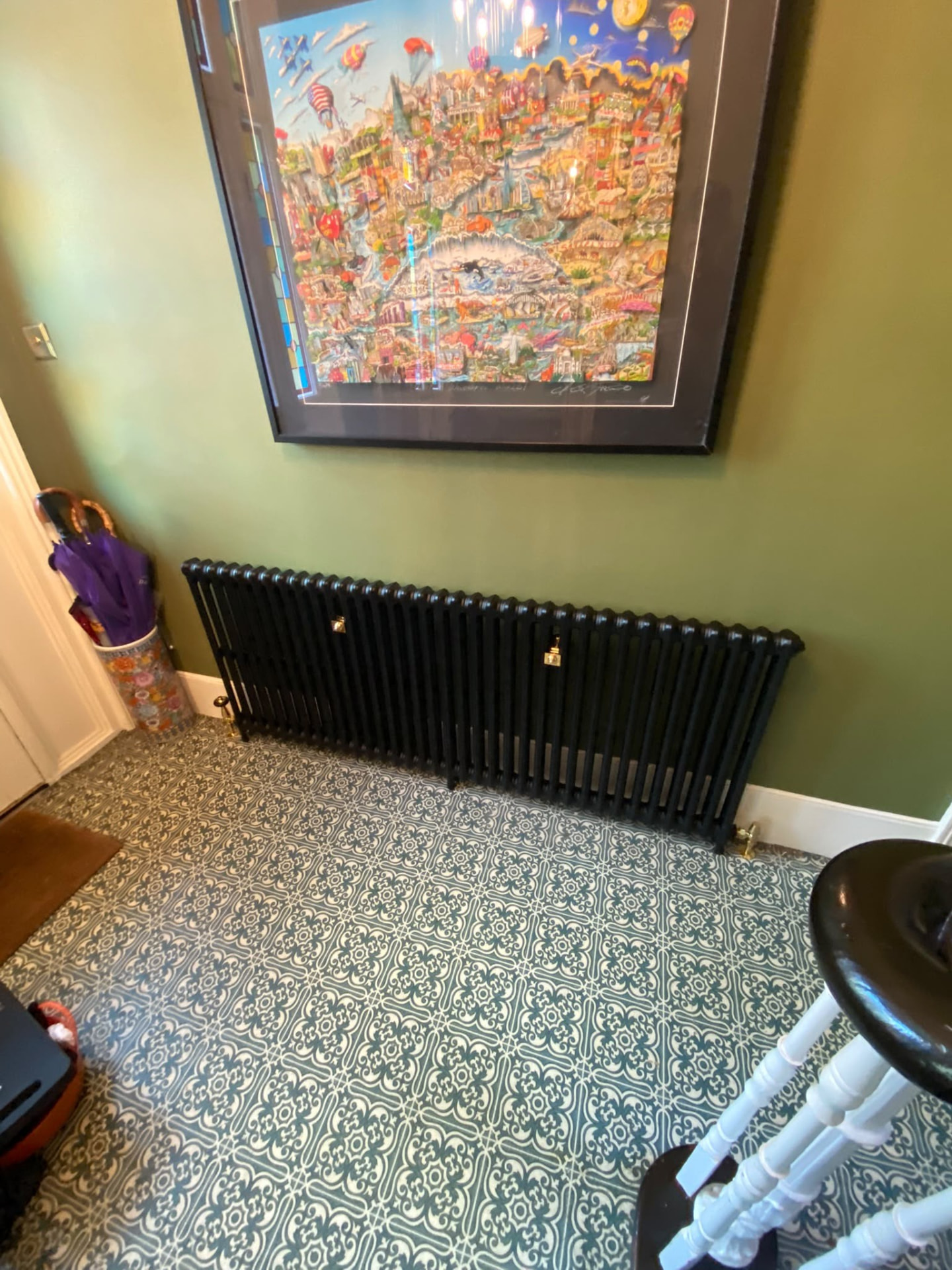 Cast iron radiator installation beneath framed artwork in a London home