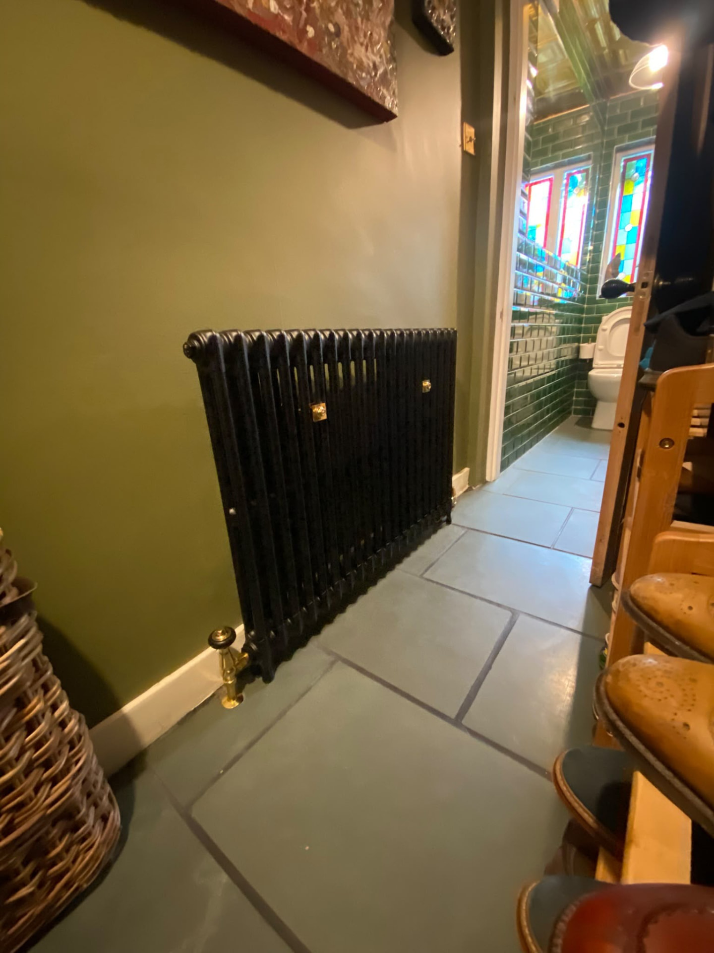 Cast iron column radiator against a dark green wall in a London home