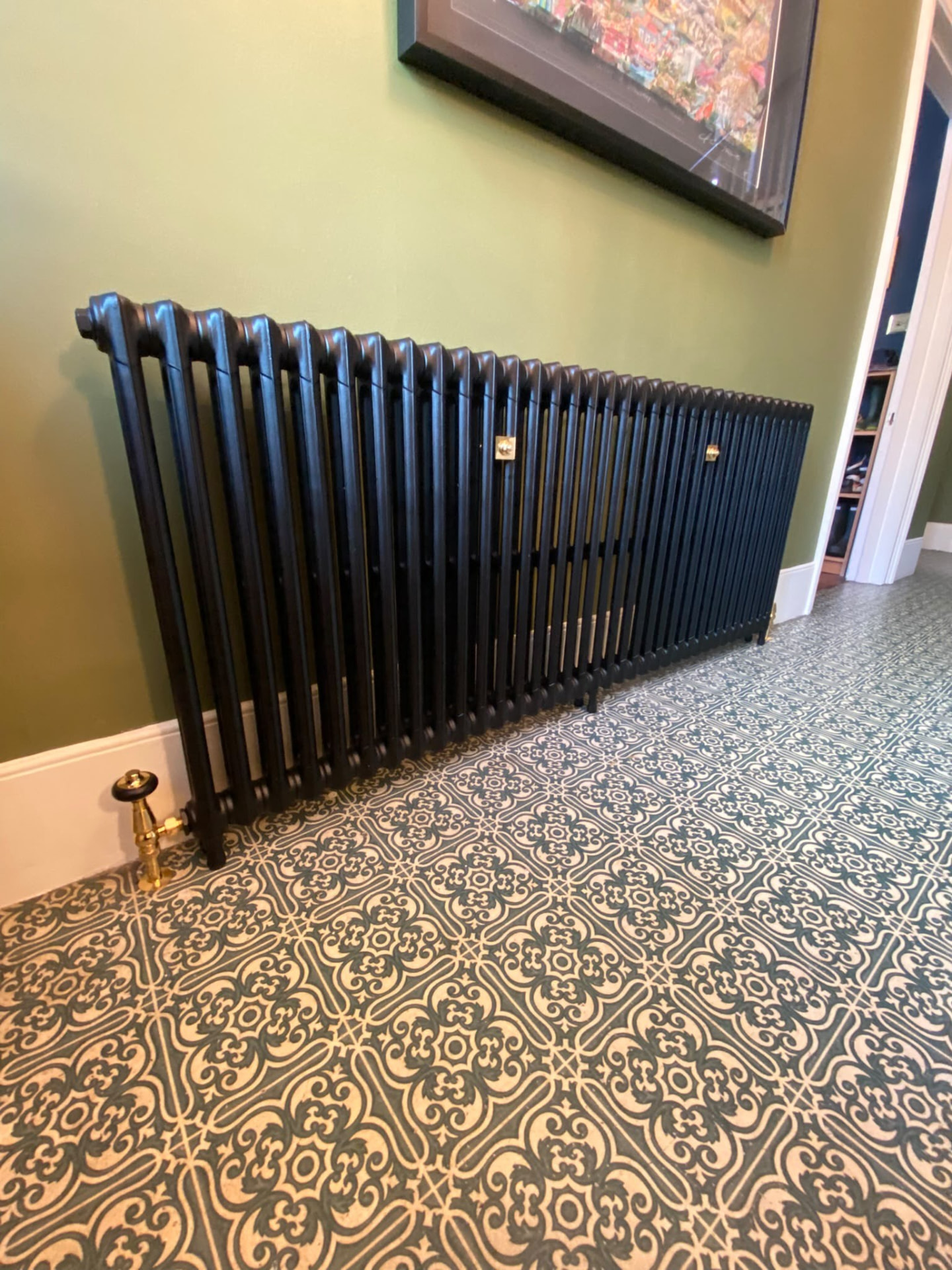 Low-angle view of a black cast iron radiator on ornate floor tiles in London