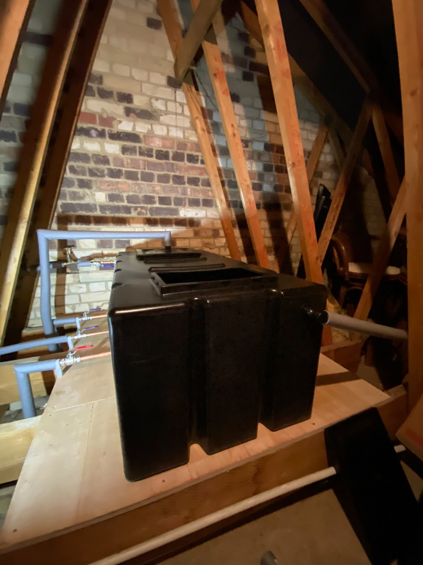 New black plastic cold water storage tank installed on a loft platform in London