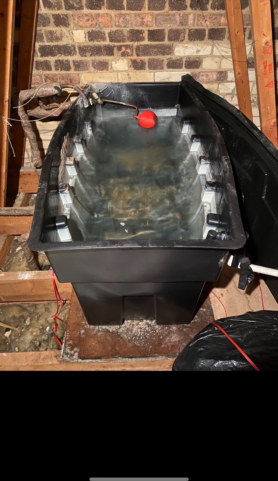 Interior of an old open-top cold water storage tank with float valve in London